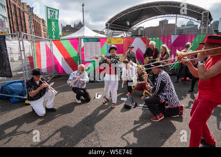 Glasgow, Schottland, Großbritannien. 28. Juli 2019. Die Musiker aus dem Zehnten Avenue Band aus Newcastle Upon Tyne während der Merchant City Festival Feiern Es ist dritten Jahr, die encontro Street Band Festival ist eine Koproduktion zwischen Oi Musica und SambaYaBamba und umfasst alle Arten von street Drumming, Karneval Messing, New Orleans Marching Band, Afro-brasilianische Percussion, gerade nach oben, Samba und vieles mehr. Credit: Skully/Alamy leben Nachrichten Stockfoto