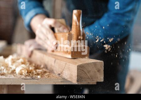 Tischler arbeiten mit Flugzeug auf Holz- Hintergrund. Stockfoto