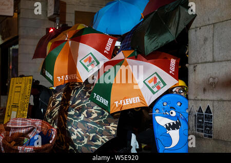 Demonstranten nehmen Deckung hinter einem Sonnenschirme bei den Auseinandersetzungen. . Zehntausende pro-demokratischen Demonstranten marschierten in Central Hongkong in einer weiteren Runde der anti Regierung Demonstration. Die Bereitschaftspolizei hat Tränengas und Gummigeschossen gegen Demonstranten trotz der Tatsache, dass die Polizei wurde weitgehend von der Öffentlichkeit für die unverhältnismäßige Anwendung von Gewalt gegen die Demonstranten in den vergangenen Demonstrationen durch die umstrittene Auslieferung Rechnung, die von der Regierung von Hongkong ausgelöst lobte verwendet. Stockfoto