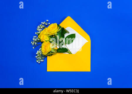 Gelbe Rosen und weißen Gypsophila im Umschlag close-up auf blauem Hintergrund. Ansicht von oben, flach. Vorlage für die Grußkarte. Festliche floral background Stockfoto