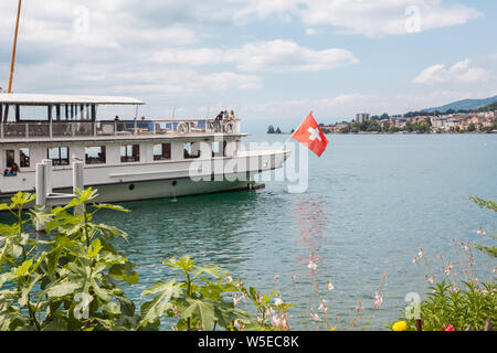 Die Belle Epoque retro Paddelboot mit Schweizer Flagge am Heck günstig in Montreux, Genfersee (Lac Leman), Waadt, Schweiz am sonnigen Sommertag Stockfoto