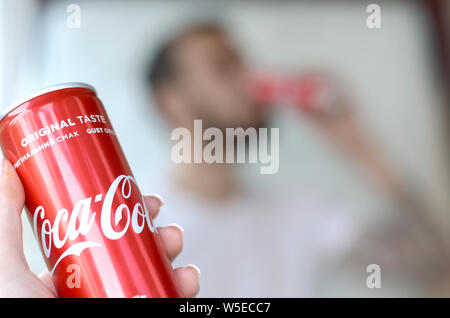 Charkow, Ukraine - 15. JULI 2019: Kaukasischer mann Getränke Coca-Cola Drink in Garage Innen- und Außengewinde Hand stellt eine Coca Cola Rot kann im Fokus. Coca Stockfoto