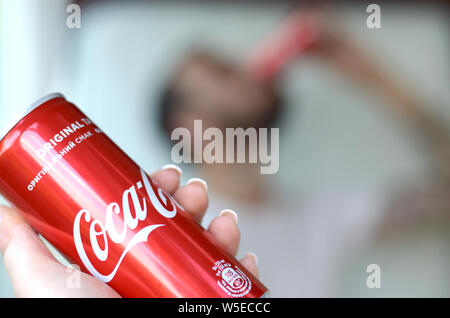 Charkow, Ukraine - 15. JULI 2019: Kaukasischer mann Getränke Coca-Cola Drink in Garage Innen- und Außengewinde Hand stellt eine Coca Cola Rot kann im Fokus. Coca Stockfoto