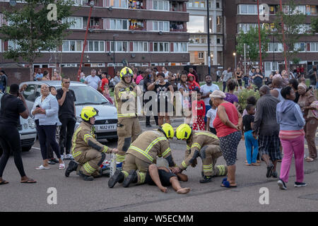 London, Großbritannien. 28. Juli 2019. Ein Bewohner zusammen und ist für den Schock nach schnell verlassen, behandelt. Acht Löschfahrzeuge und Rund 60 Feuerwehrleute aus London Feuer Brücke gegen eine "kleine" Hochhaus blaze, die um 8:40 Uhr auf dem 8. Stock in den Müll rutsche Bereich Eddystone Turm, ein 22-stöckiges Hochhaus, Teil von Deptford's Pepys Immobilien in South East London. Eine Anzahl von Bewohnern hatte das Gebäude vor feuerwehrmänner am Tatort eintraf, Links, mit anderen verbleibenden "sicher in ihren Wohnungen". Credit: Guy Corbishley/Alamy leben Nachrichten Stockfoto