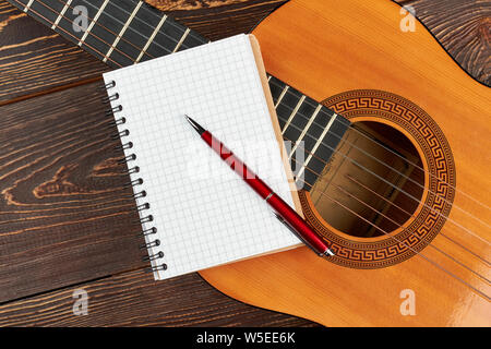 Leeres Notizbuch und Stift auf Gitarre. Stockfoto