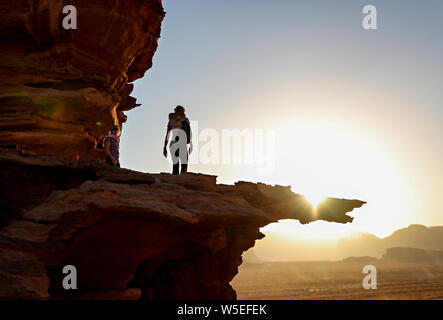 Eine Frau, die zu Fuß auf einem Felsvorsprung im Wadi Rum bei Sonnenuntergang. Stockfoto