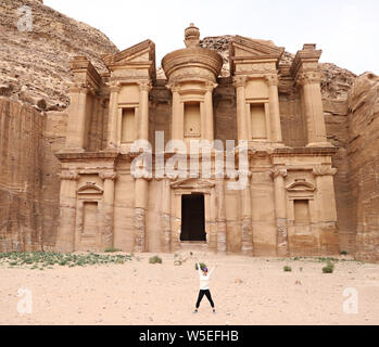 Frau steht in der Freude mit den Armen vor dem Kloster in Petra in Jordanien. Stockfoto