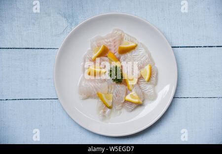 Roher Fisch Filet Stück mit Zitrone auf weiße Platte/Close up Pangasius dolly Fisch Fleisch Stockfoto