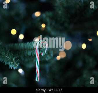 Traditionelle künstlicher Weihnachtsbaum mit Zuckerstange und weiße Lichter leuchten im Hintergrund Stockfoto