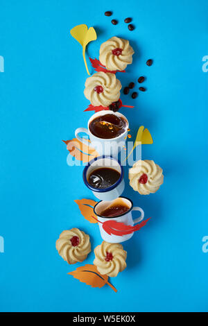 Herbst, ausgleichende Turm von Spritzen, Kaffeetassen, Cookies und Blätter im Herbst auf blauem Hintergrund Stockfoto