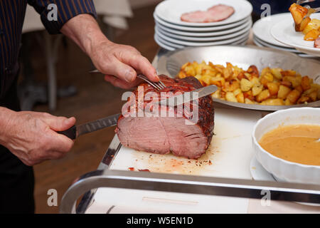 Koch ist Schneiden Beefsteak mit schinkenmesser von der Guest Relation Stockfoto