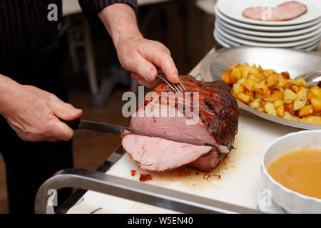 Koch ist Schneiden Beefsteak mit schinkenmesser von der Guest Relation Stockfoto