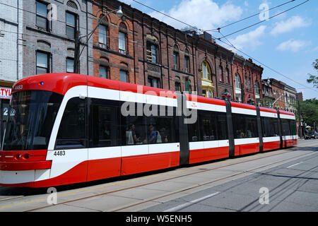 TORONTO - Juli 2019: Eine moderne artikulieren Straßenbahn vorbei an alten viktorianischen Gebäude in der Queen Street. Stockfoto