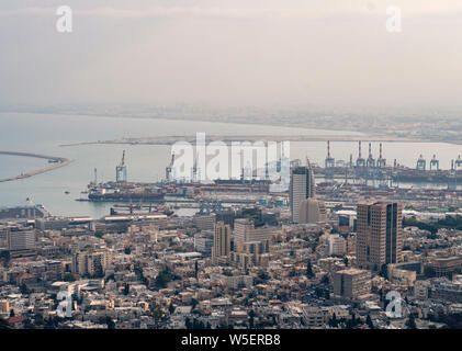 Blick auf den Hafen von Haifa in Israel kurz an einem bewölkten Tag. Indusrtial Teil von Haifa mit Docks und Fähre Schiffe. Gebäude der Stadt am Meer. Touristische attraktive Stockfoto