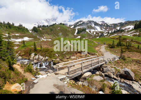 Wunderschöne Aussicht auf eine Spur und eine Brücke über den Fluss durch die Berglandschaft der an einem sonnigen Sommertag umgeben. Im Paradies, Mt Rainier Na genommen Stockfoto