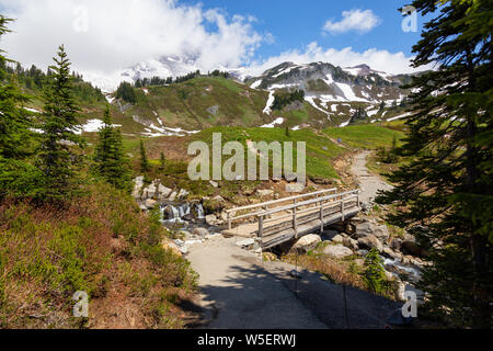 Wunderschöne Aussicht auf eine Spur und eine Brücke über den Fluss durch die Berglandschaft der an einem sonnigen Sommertag umgeben. Im Paradies, Mt Rainier Na genommen Stockfoto