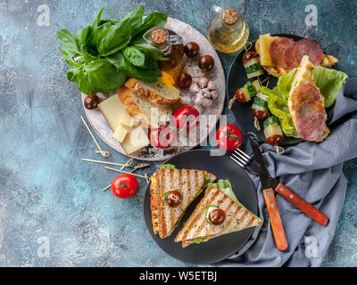 Toast mit Rührei und geräuchertem Fleisch, Gemüse und Käse. Tomaten und Gewürzen. Köstliches Frühstück und Snacks. Ansicht von oben Stockfoto