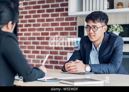 Junge asiatische Geschäftsmann und Geschäftsfrau Sprechen über business-Vereinbarung in der Sitzung Tabelle in modernen Büro. Business Partnership Konzept. zufrieden. Stockfoto