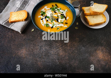 Blick von oben auf die Grenze aus traditionellen Kürbis Suppe und Brot auf dunklen vintage Holz- Hintergrund. Stockfoto