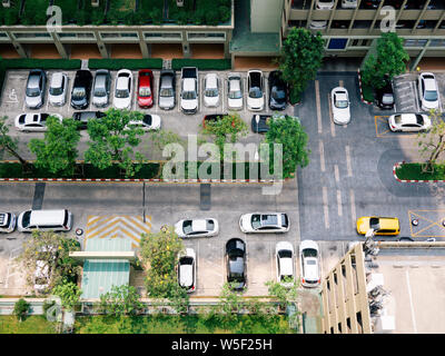 Ansicht von oben, Parkplatz bei der Wohnung. Luftaufnahme von Apartment garage mit voller überdachten Parkplatz, Autos und grüne Bäume von mehrstöckigen Wohnhaus Stockfoto