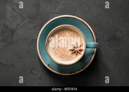 Masala Indischen Tee oder Kaffee in blauer Schale mit Gewürzen und Zimt auf schwarzem Beton Tabelle. Ansicht von oben. Stockfoto