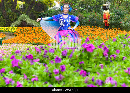 Ein Entertainer gekleidet in einem bunten Rock mit Blumen dekoriert, stellt auf der Guangzhou Chimelong Tourist Resort in der Stadt Guangzhou, Südchina Gua Stockfoto