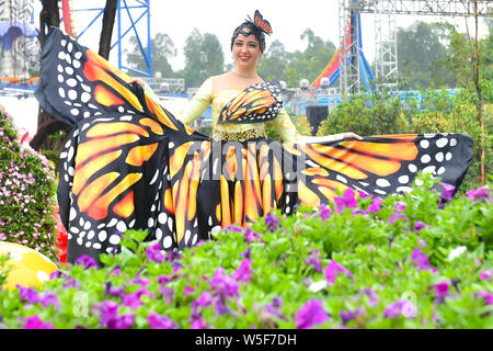 Ein Entertainer gekleidet in einem bunten Rock mit Blumen dekoriert, stellt auf der Guangzhou Chimelong Tourist Resort in der Stadt Guangzhou, Südchina Gua Stockfoto