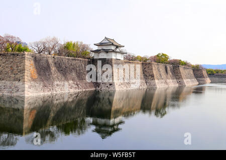 Turm und Mauer der Burg von Osaka, Japan. UNESCO-Weltkulturerbe. Wand- und Turm sind im Wasser des Teiches wider Stockfoto