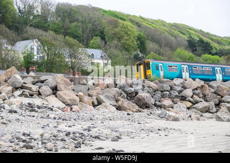 Zug, Bahn, vorbei an Meer Abwehr, Fels, Stein, Wand, in der Nähe der, ferryside Zug, Bahnhof, Ferryside, Strand, Carmarthenshire, West Wales, UK, GB, Großbritannien, Britische Stockfoto