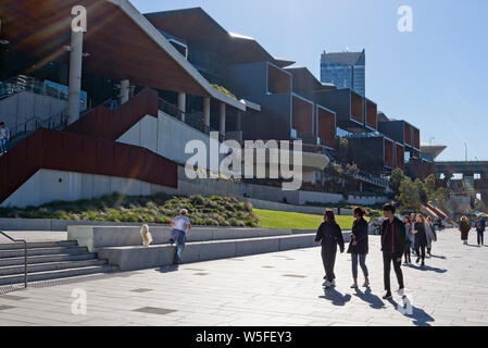 Fußgänger zu Fuß entlang der Promenade in der Nähe von Darling Harbour, Sydney mit dem International Convention Centre im Hintergrund. Stockfoto