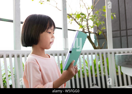 Asiatische kleinen chinesischen Mädchen lesen Buch im Café im Freien Stockfoto