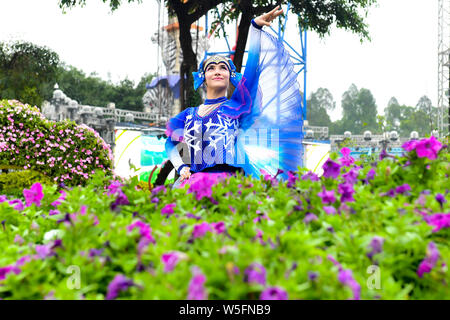 Ein Entertainer gekleidet in einem bunten Rock mit Blumen dekoriert, stellt auf der Guangzhou Chimelong Tourist Resort in der Stadt Guangzhou, Südchina Gua Stockfoto