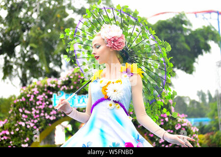 Ein Entertainer gekleidet in einem bunten Rock mit Blumen dekoriert, stellt auf der Guangzhou Chimelong Tourist Resort in der Stadt Guangzhou, Südchina Gua Stockfoto