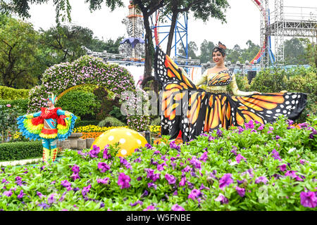 Ein Entertainer gekleidet in einem bunten Rock mit Blumen dekoriert, stellt auf der Guangzhou Chimelong Tourist Resort in der Stadt Guangzhou, Südchina Gua Stockfoto