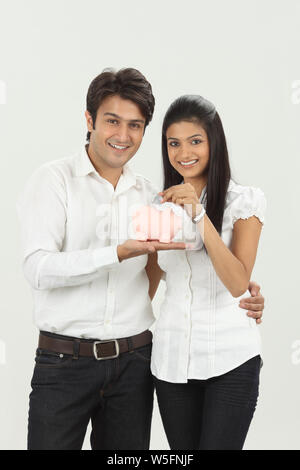 Frau, eine Münze in ein Sparschwein mit ihrem Ehemann Stockfoto