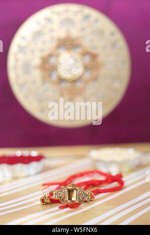 Indian Festival: Raksha Bandhan Hintergrund mit einem eleganten Rakhi, Reis Körner und Kumkum. Ein traditionelles indisches Armband, ist ein Symbol der Liebe. Stockfoto