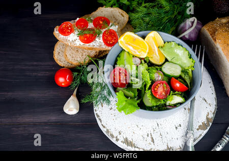 Salat von frischem Salat, Tomaten, Gurken, Rettich, grünen und Zwiebeln für das Mittagessen auf dem Tisch. Gesunde Ernährung Konzept. Platz kopieren Stockfoto