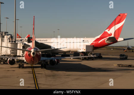 Eine Qantas Airbus 330 und ein kleines Flugzeug bei den inländischen Flug terminal in Sydney (Kingsford Smith) Airport in der Nähe von Sydney in New South Wales, Australien Stockfoto
