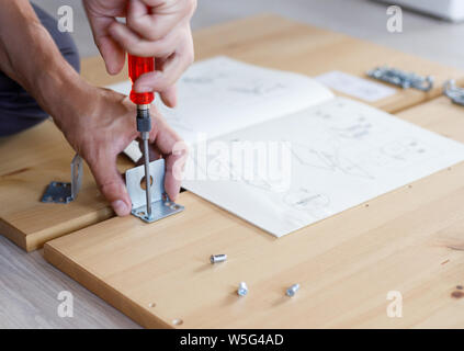 Mann Zusammenbau von Möbeln zu Hause mit einem Schraubendreher. Stockfoto