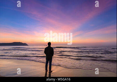 Silhouette der Mann am Strand von magischen dramatischer Sonnenaufgang suchen. Der Mann stand am Sandstrand Stockfoto