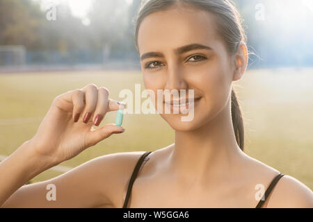 Schöne Frau mit dunklen Haaren hält in ihrer Hand farbigen Pillen Ergänzungen, Sport, Vitamine, Diät, Ernährung, gesunde Ernährung, Lebensstil. Stockfoto