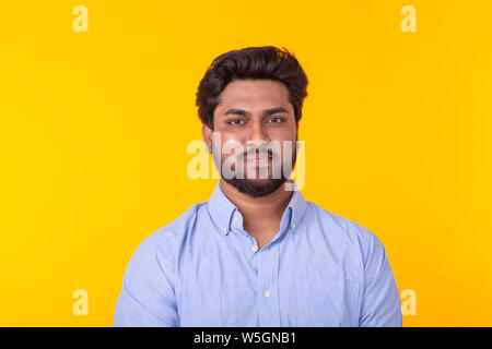 Indische stattlicher Mann mit blauem Hemd auf gelbem Hintergrund Stockfoto