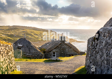 Gearrannan, Shottland - Juni 20, 2018: Gearrannan blackhouse Village mit strohgedeckten Häuser auf der Insel Lewis in einem goldenen Abendlicht Stockfoto