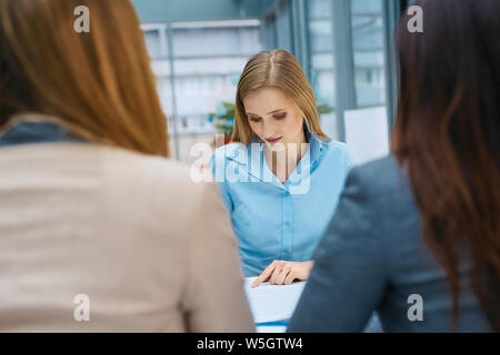 Junge Frau unterzeichnen Vertrag nach dem Vorstellungsgespräch bei modernen Büro Stockfoto