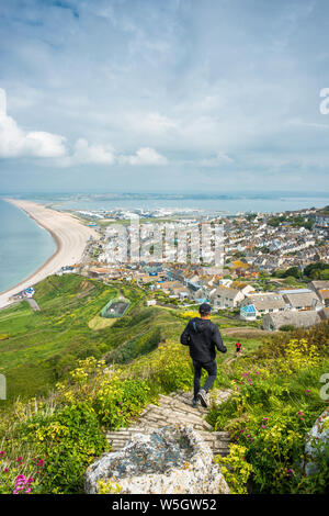 Joggern den Weg nach unten zu Chesil Beach aus Portland Höhen auf der Isle of Portland, Dorset, England, Vereinigtes Königreich, Europa Stockfoto