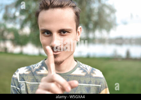 Ein Kerl mit einem schlauen Ausdruck auf seinem Gesicht, zeigt einen Finger Geste, nicht versuchen, mich zu betrügen Stockfoto