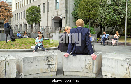 Büroangestellte Personen, die im Sommer in der City of London, England, Großbritannien, IM Garten des Fen Court bei 120 Fenchurch draußen auf Betonsitzen SITZEN, KATHY DEWITT Stockfoto