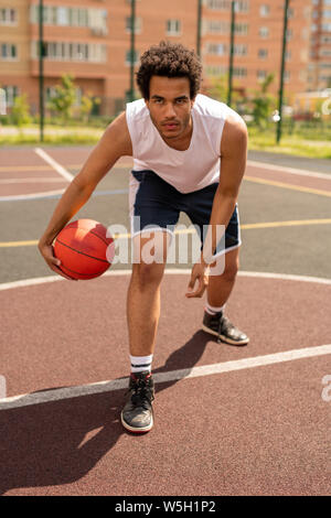 Ernsthafte junge Basketballspieler, Kugel zu werfen, während man durch die weiße Linie Stockfoto