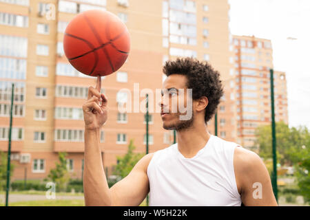 Junge aktive professioneller Basketballspieler Holding rotierende Kugel auf Zeigefinger Stockfoto
