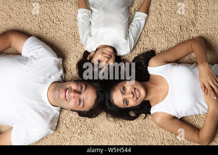 Erhöhte Ansicht einer Familie liegend am Boden lächelnd Stockfoto